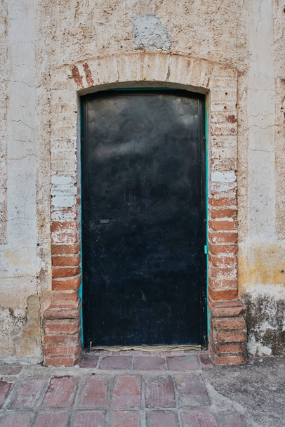 Worn and unpainted facade with a metal door with copy space - 写真・画像