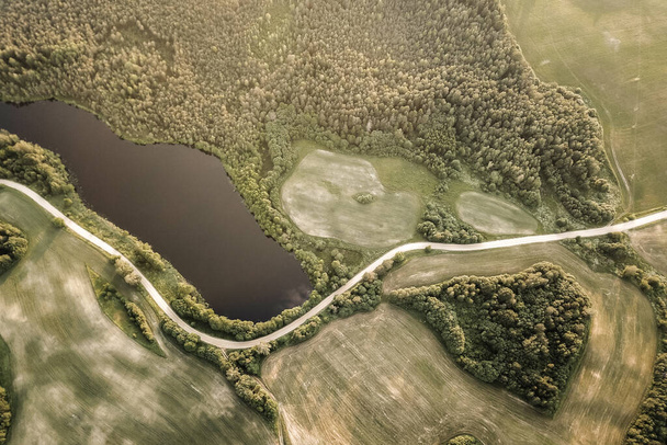 Aerial view of lake and forest. Small blue lake in green forest and fields - Zdjęcie, obraz