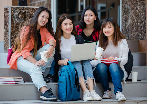 Grupa czterech młodych atrakcyjnych azjatyckich studentek studiujących razem w kampusie uniwersyteckim na świeżym powietrzu, patrzących przed kamerą. Koncepcja edukacji, przyjaźni i życia studenckiego. - Zdjęcie, obraz