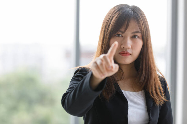 Negócio de comprimento total em terno preto. Mulher de negócios asiática apontando o dedo para a frente para trabalhar monitor inteligente. Mulher trabalhadora bonita e confiante - Foto, Imagem