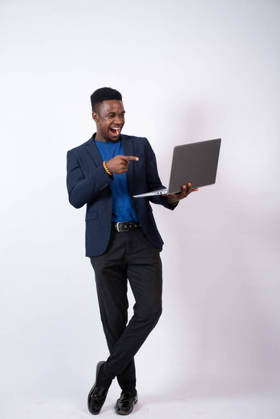 An African businessman in a suit with a laptop in front of a white wall - Foto, Imagem