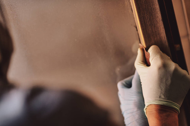 vrouw handen verwijderen van verf en het gebruik van schuurpapier op de ramen van haar huis, en vervolgens opnieuw schilderen door het hout te bewerken met kracht en vaardigheid, zonder de noodzaak om een timmerman te bellen, zeer goed in doe-het-zelf - Foto, afbeelding