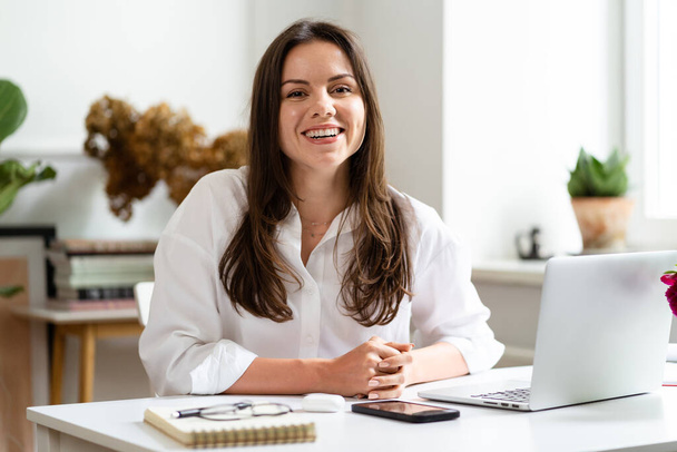 Bizneswoman pracuje na laptopie siedząc w domu i zarządzając swoją firmą za pośrednictwem biura - Zdjęcie, obraz