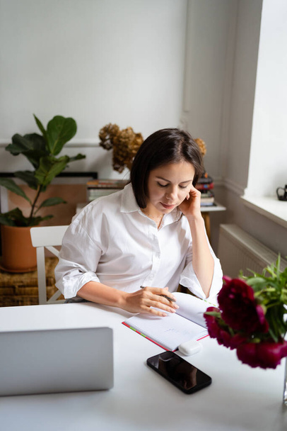 Femme d'affaires travaillant sur ordinateur portable assis à la maison et la gestion de son entreprise via le bureau à domicile - Photo, image