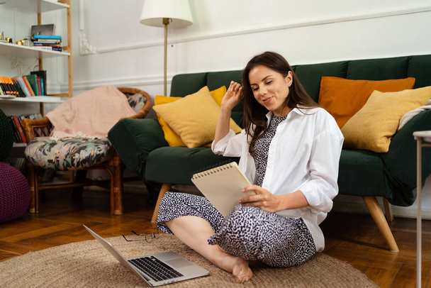 Businesswoman working on laptop computer sitting at home and managing her business via home office - Photo, image