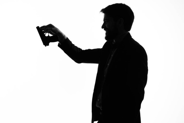 手に銃を持ったスーツの男犯罪の手のジェスチャー光の背景 - 写真・画像