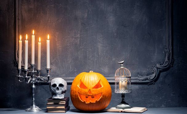 Scary laughing pumpkin and old skull on ancient gothic fireplace. Halloween, witchcraft and magic. - Фото, изображение