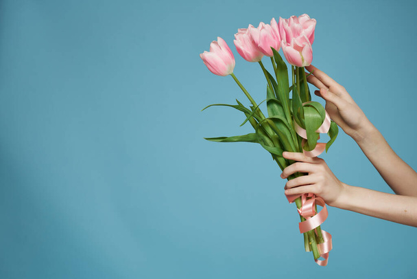 μπουκέτο από ροζ λουλούδια στο χέρι ρομαντικό δώρο μπλε φόντο - Φωτογραφία, εικόνα