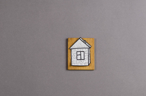 Paper figure of a painted house on a yellow wooden board. Hand-d - Φωτογραφία, εικόνα