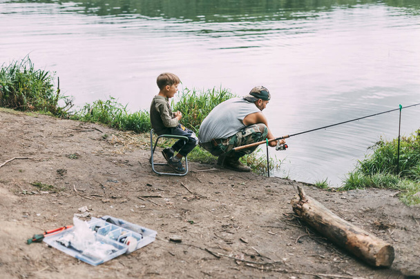 Un jeune homme apprend à ses enfants à pêcher pendant des vacances en famille dans un camping. Ses loisirs, vacances, week-end, pêche - Photo, image