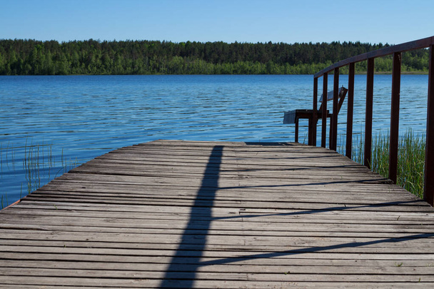Ponts en bois avec balustrades et banc qui entrent dans le lac bleu. - Photo, image