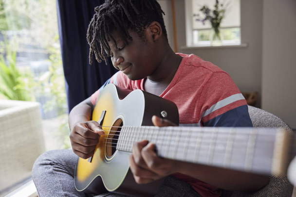 Teenage Boy Learning To Play Acoustic Guitar At Home - Valokuva, kuva