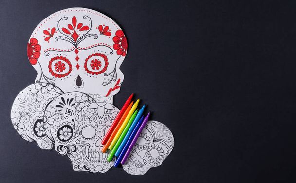 メキシコの休日の準備Dia de los Muertos 。カトリーナのマスクを黒の背景に描き、色鉛筆と旗、平らなレイアウトで - 写真・画像