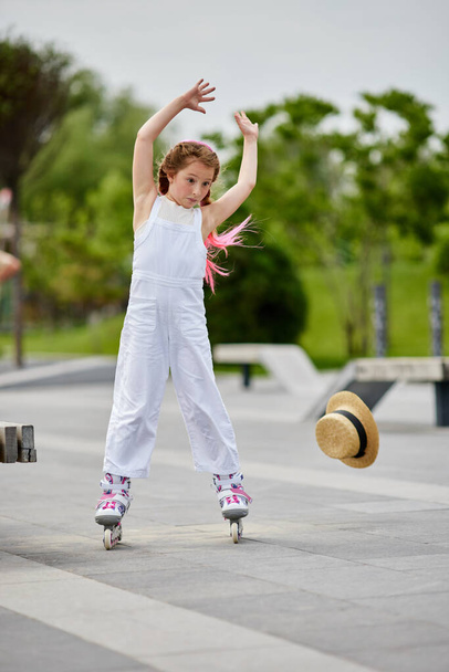 Cute little child girl on roller skates at park - Photo, image
