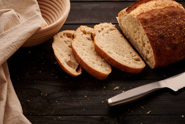 Freshly baked homemade tartine bread on dark wooden table - Foto, afbeelding
