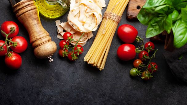 Italian cuisine food ingredients. Pasta, tomatoes, basil and spices. Top view flat lay with copy space - Photo, Image