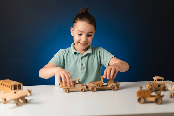 Кавказька дитина грає на дерев "яній іграшці на столі. - Фото, зображення