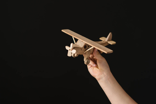 Hand hält ein Flugzeugmodell in der Hand über schwarzem Hintergrund - Foto, Bild