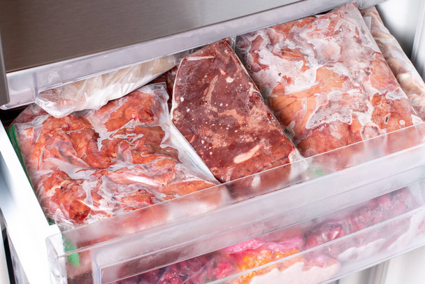 Pakastin, joka on täytetty lihalla ja jäädytetyillä tuotteilla. Liha jäädytetty muovipussit Food Reserve varastoidaan elintarvikkeiden valmistukseen. Jäädytetyt elintarvikkeet - Valokuva, kuva