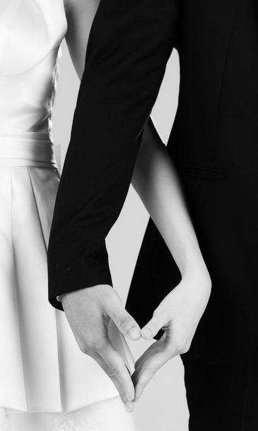 Selectieve focus van bruid en bruidegom handen samenvoegen maken hart teken. Concept voor de huwelijksfotografie. - Foto, afbeelding