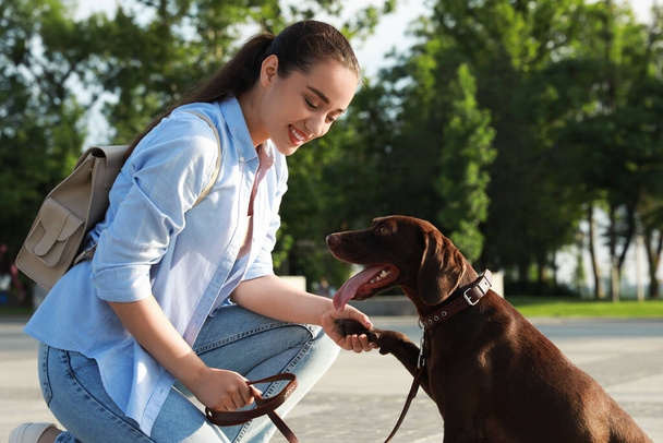 Young woman with her German Shorthaired Pointer dog on city street - Photo, Image