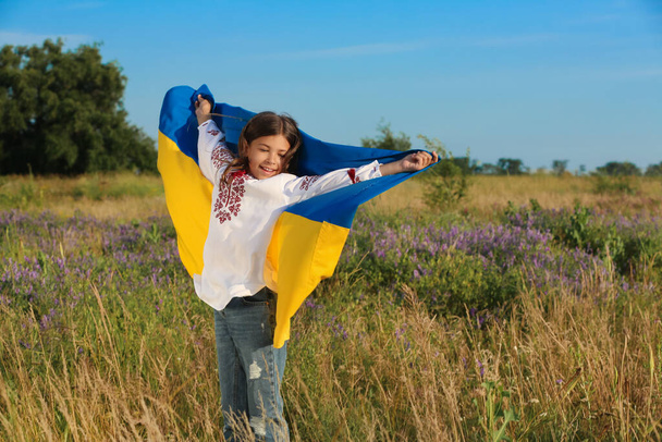 Happy girl with national flag of Ukraine in field - Foto, Imagem