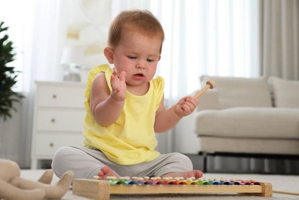 Милая рыжая малышка играет с ксилофоном дома - Фото, изображение