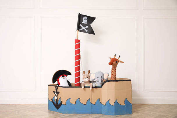 Pirate cardboard ship and toys near white wall indoors - 写真・画像