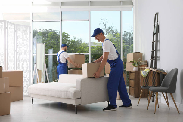 Moving service employees with cardboard boxes in room - Фото, изображение
