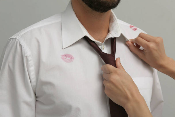 Woman noticed lipstick kiss marks while straightening her husband's shirt and necktie, closeup - Photo, image