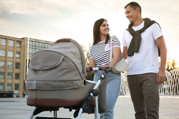 Happy parents walking with their baby in stroller outdoors - Foto, Imagem