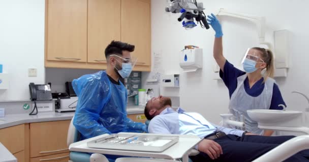 Caucásico médico femenino y masculino que mueve la máquina de rayos X para examinar el problema del diente del paciente masculino  - Metraje, vídeo