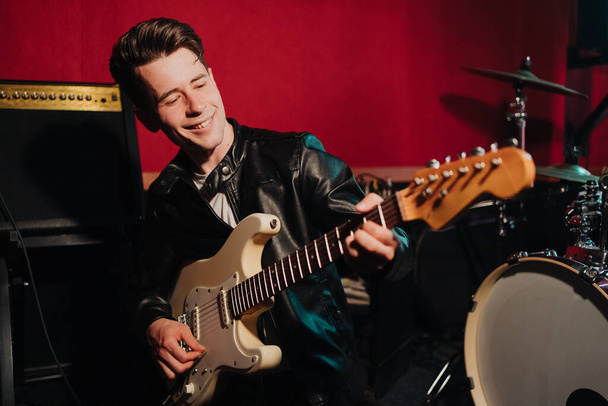 Fiatal férfi hipster felvétel új hangok stúdióban, miközben játszik elektro gitár és ének - Fotó, kép
