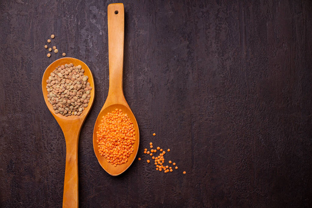 raw red lentils in wooden spoons on a dark background - Photo, Image