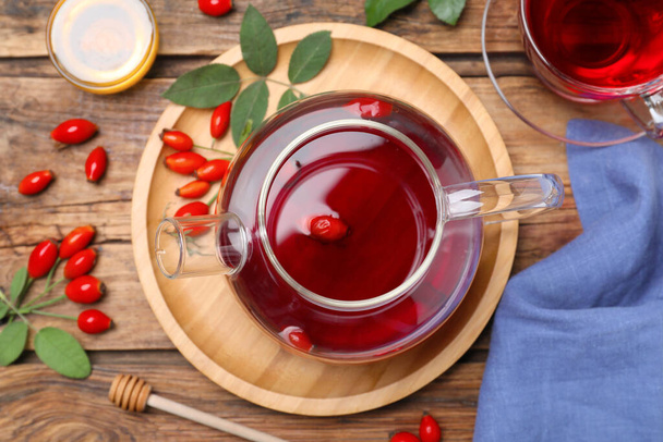 Flat lay composition with aromatic rose hip tea on wooden table - Fotoğraf, Görsel