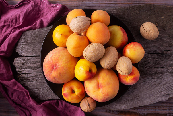 желтые фрукты - персики, абрикосы, сливы на деревянном фоне - Фото, изображение