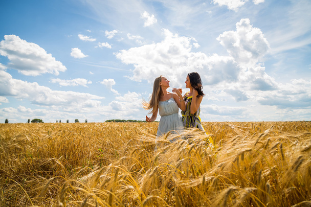 Chicas de pie en un campo de trigo
. - Foto, Imagen