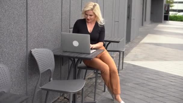 Fiatal üzletasszony dolgozik a számítógépnél a kávézóban. Fiatal lány downshifter dolgozik egy laptop, munkanapon. - Felvétel, videó