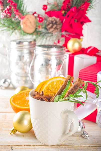Bebida alcohólica caliente tradicional de invierno. Vino caliente en una taza blanca en el fondo de la mesa de la cocina con decoraciones de Navidad. - Foto, imagen