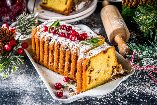 Traditional christmas baking, Festive Xmas fruitcake with dryed fruits, liquer, and cranberry decor. Homemade fruitcake on Chritmas decorated background - Fotó, kép