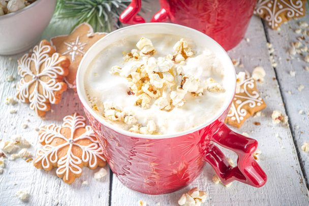 Popcorn latte koffiemok. Trendy warme drank, latte met gezouten kaas popcorn, met winter kerstversiering, witte houten achtergrond kopieerruimte - Foto, afbeelding