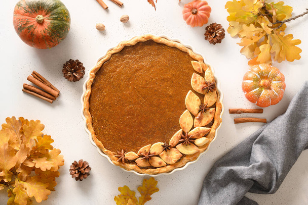 Homemade tasty pumpkin pie with autumn decorations and leaves for Thanksgiving Day on white. - Fotó, kép