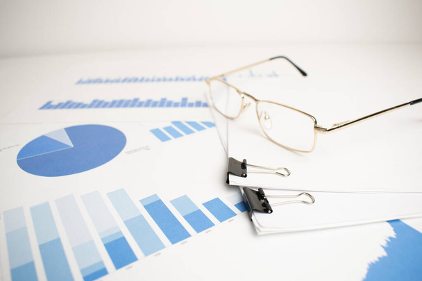 The glasses were placed on the data report documents, graphs and charts for preparation of the business plan. - Foto, Imagem