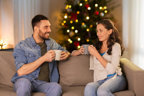 couple drinking tea or coffee at home on christmas - Foto, afbeelding