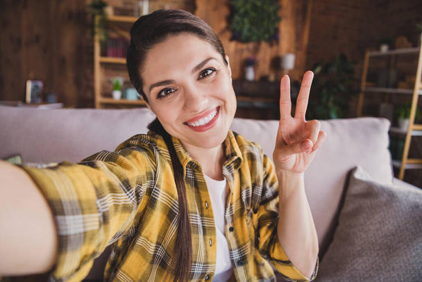Photo of young happy cheerful positive woman make vi-sign selfie smile good mood indoors inside house home - Fotografie, Obrázek