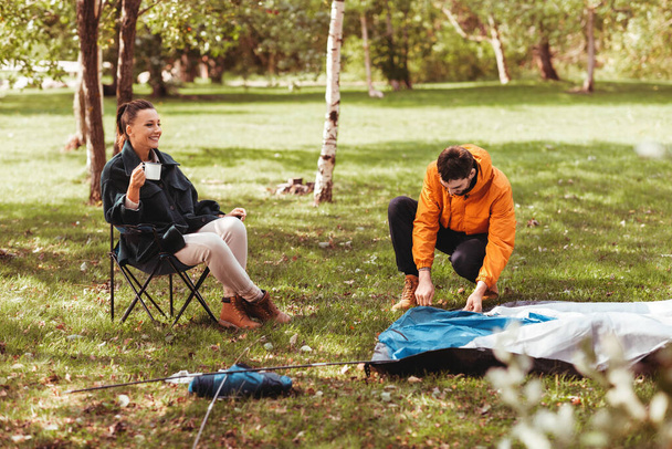 happy couple setting up tent outdoors - Foto, afbeelding