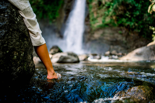 Foot of a woman in the water of a small natural lake in front of a waterfal - Fotografie, Obrázek