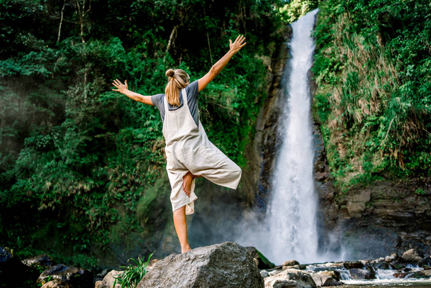 Žena stojící v józe pózuje před vodopádem v džungli - Fotografie, Obrázek