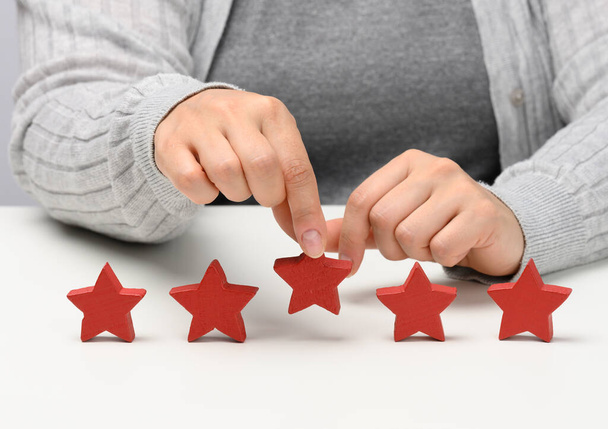 Feedback van klanten concept. Vijf rode sterren, de beste beoordeling van uitstekende diensten met een vrouwelijke hand te ontmoeten. Witte tafel - Foto, afbeelding