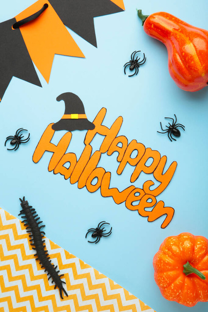 Halloween composition with spiders and pumpkins on blue background. Top view. Vertical photo. - Foto, Bild